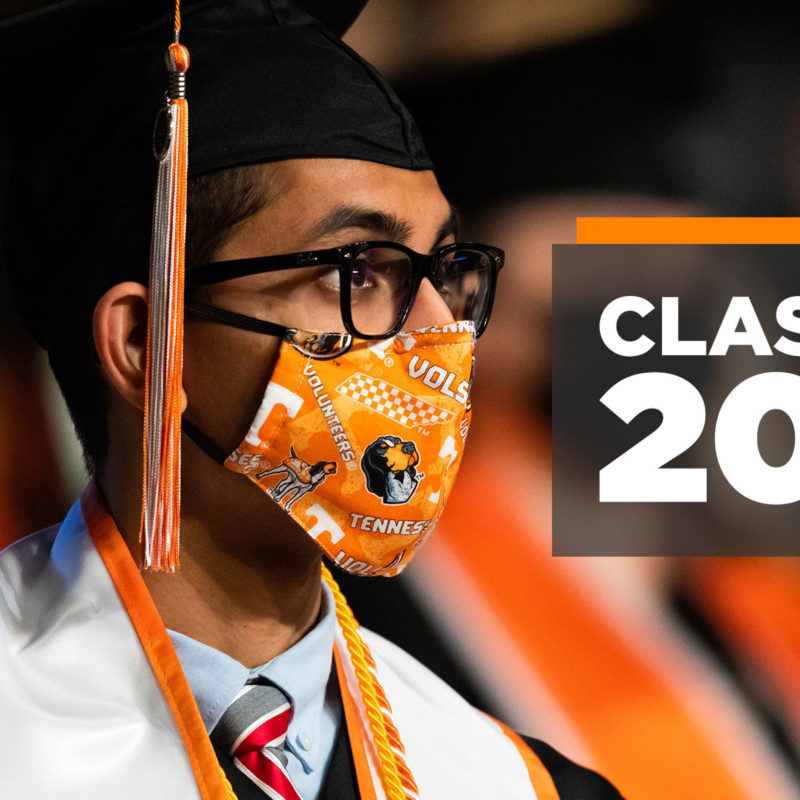 A graduating UT student in academic regalia, mortar board with orange and white tassel, and an orange UT face mask with text Class of 2021